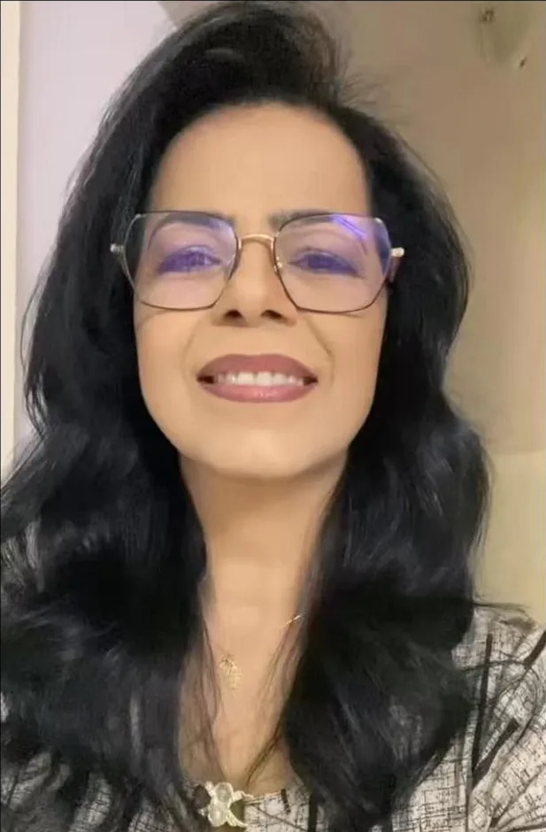 Célia Nogueira, de óculos e cabelo escuro com ondas, sorrindo